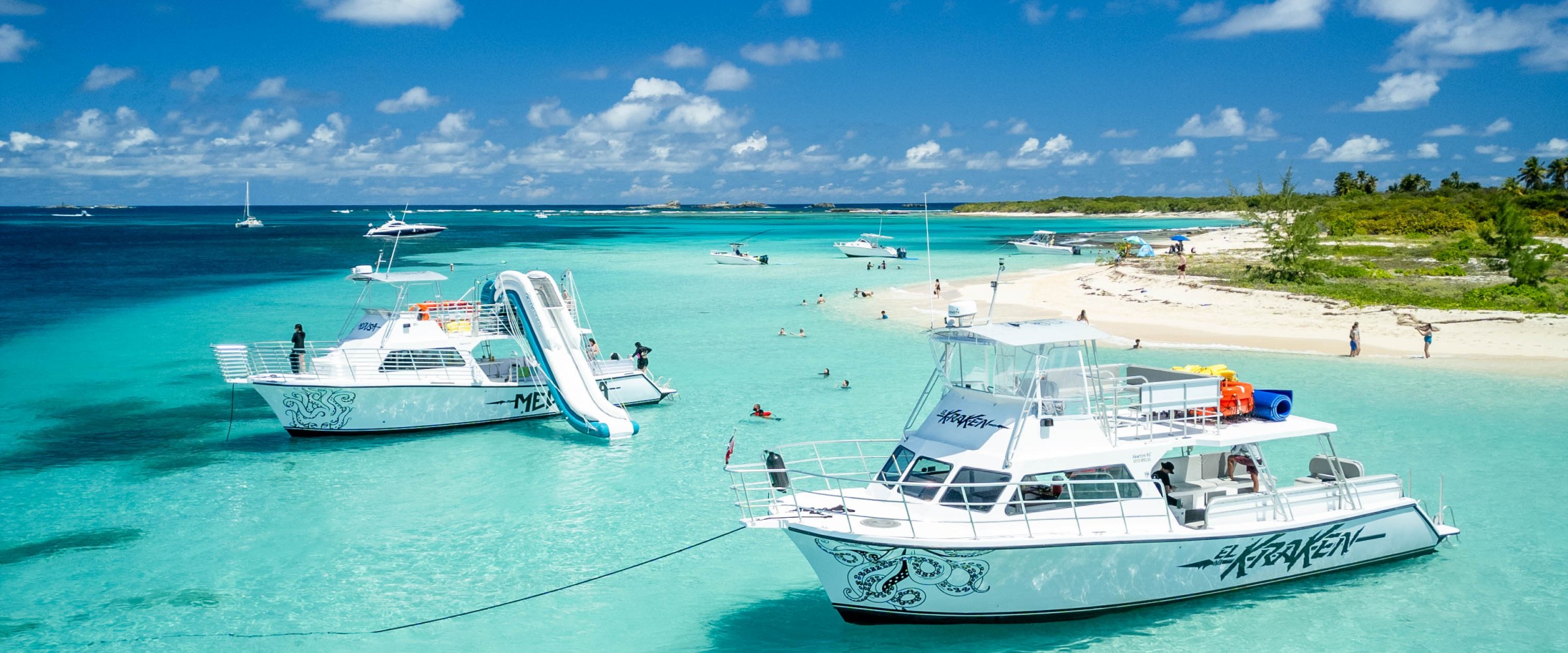 Two boats on turquoise water near a sandy beach under a clear blue sky.