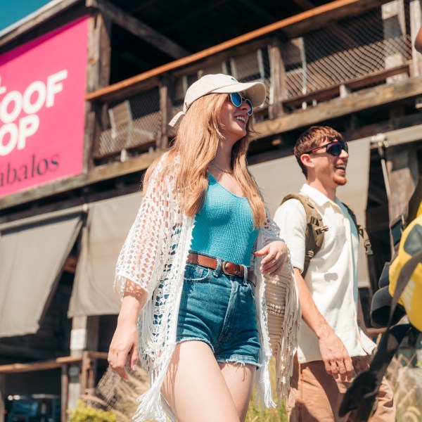 Two people walking outside a building with a sign 'El Roof Top'.